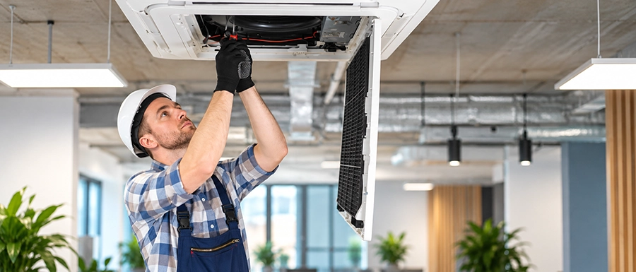 Technician servicing a ceiling cassette unit for commercial indoor air quality solutions in Calgary - Proton HVAC